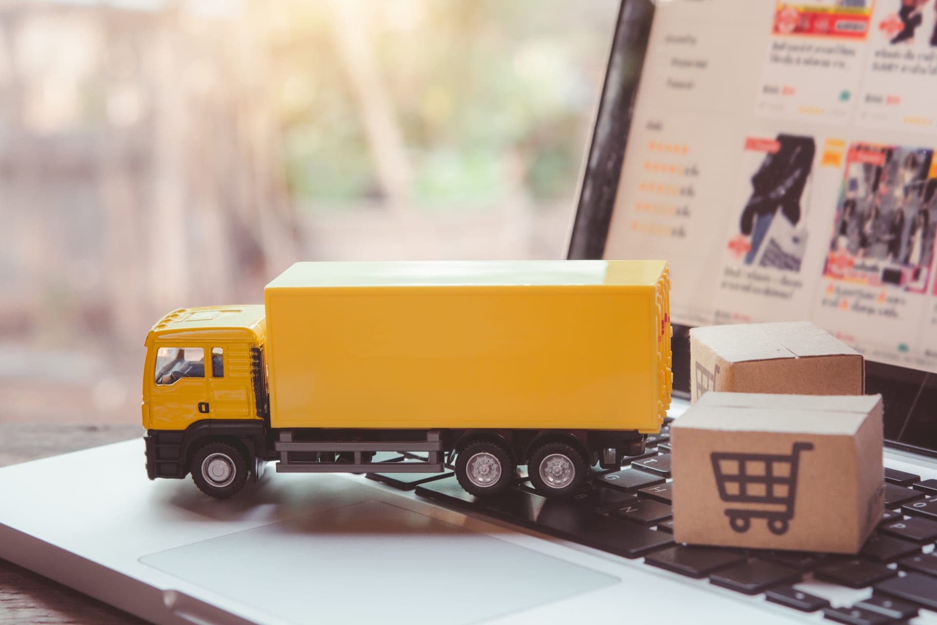 Delivery truck and shipping cartons on a laptop, representing connected order-to-delivery logistics