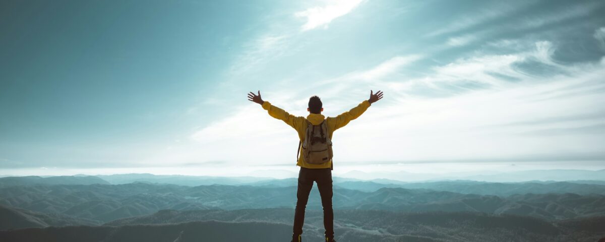 Hiker with arms up standing on the top of the mountain