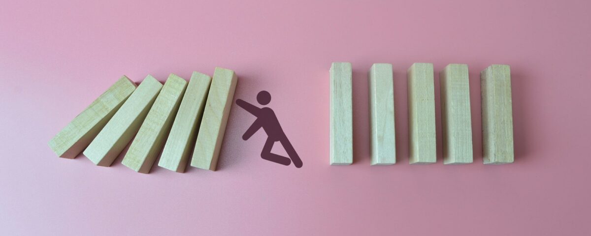 Businessman in panic against collapsing wooden blocks. Business crisis and failure concept.